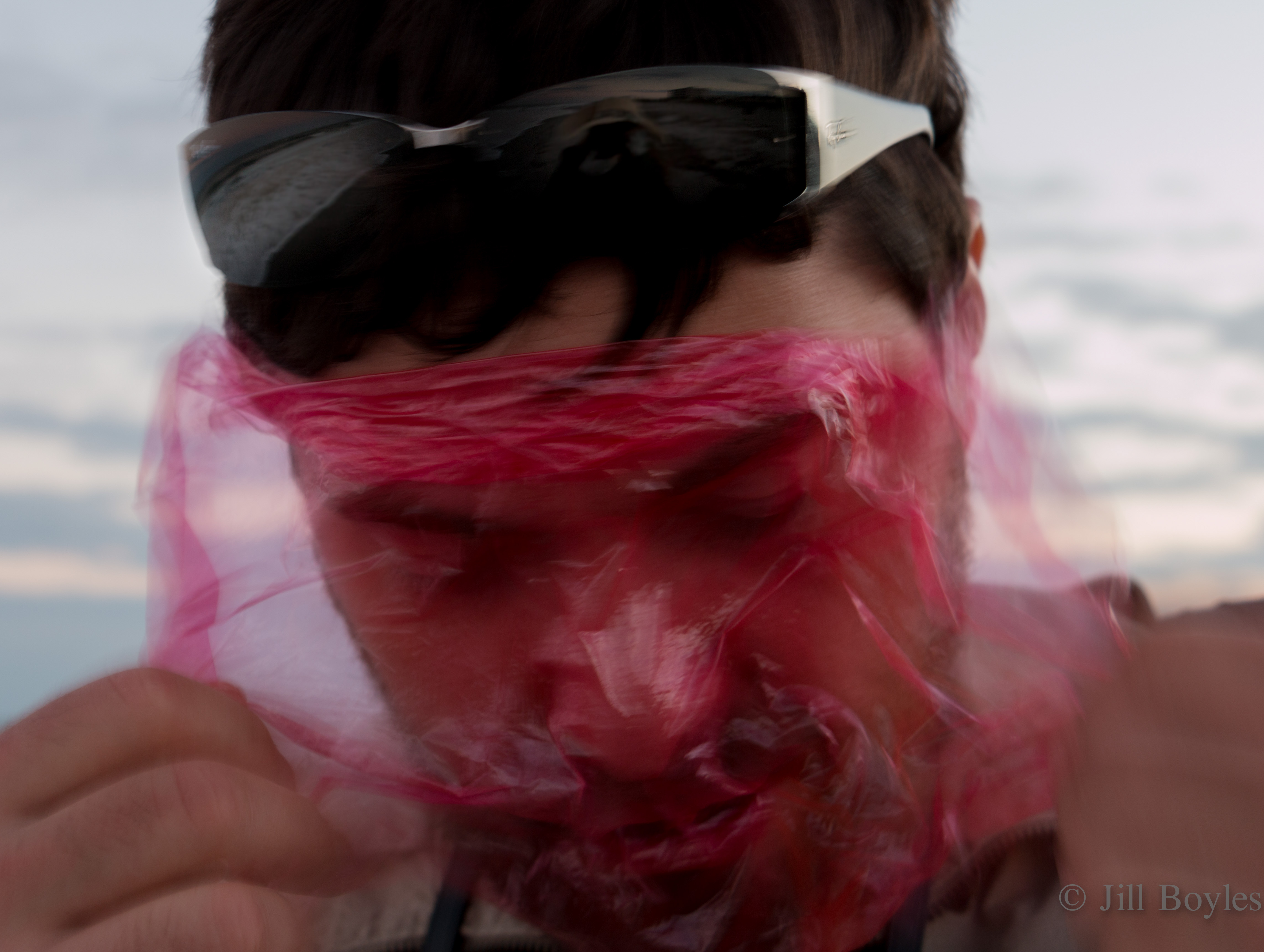 Jill Boyles photographer_man pulling red plastic wrap off his face